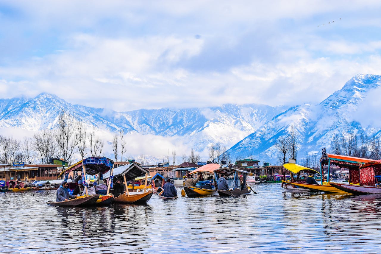 Scenic view of shikara boats on Dal Lake with snow-capped mountains in Srinagar.