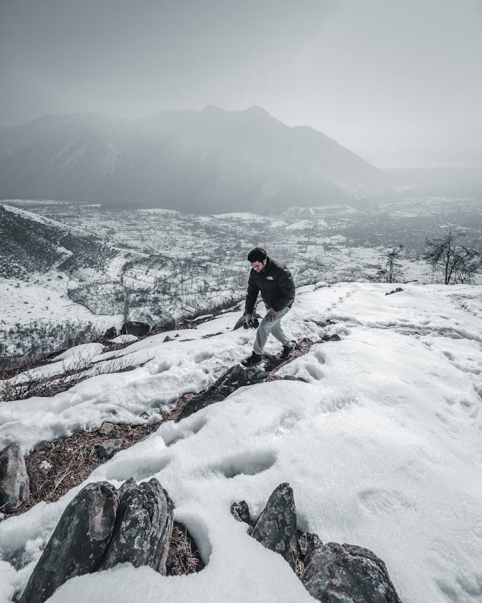 Single hiker climbing snowy mountain in Kashmir, showcasing winter adventure and scenic landscape.